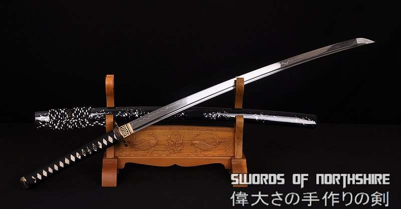 a clay tempered katana with a black tsuka